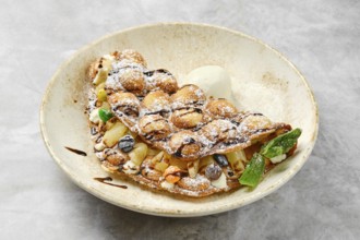 A mouthwatering dessert showcases a fluffy, golden-brown waffle filled with a variety of fresh