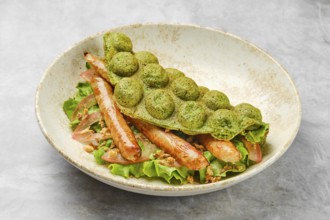 A vibrant green waffle is placed atop a bed of fresh lettuce, featuring tender grilled sausage and