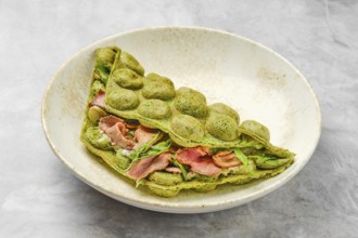 A matcha pancake showcases a vibrant green hue, folded elegantly with layers of savory ingredients