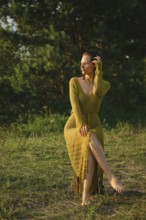 On a warm day, a woman sits gracefully by the lake surrounded by lush greenery. Wearing a fishnet