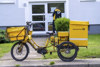 Postman, Deutsche Post, distributes the mail in an apartment building, electric tricycle, North