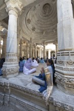 Indian woman praying between the white marble pillars in the Adinath temple in Ranakpur, Jain