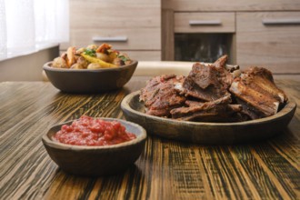 Succulent roasted beef ribs are plated alongside a vibrant vegetable medley and a bowl of spicy