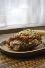 Juicy roasted turkey thigh with herbs on a wooden plate in a cozy kitchen setting