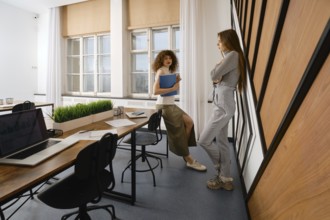 Two women are discussing the user interface of their health monitoring app in a stylish startup