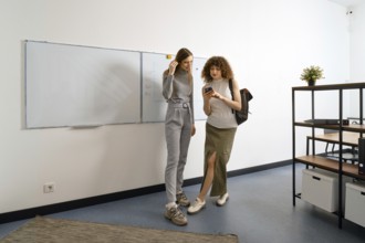 Women have finished work in coworking and call a taxi online using a mobile application in a