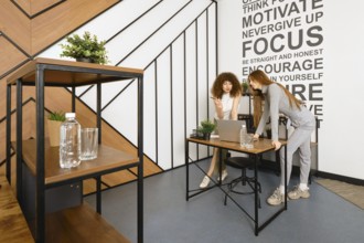 Two women are bent over a laptop and studying a prototype of their health monitoring program