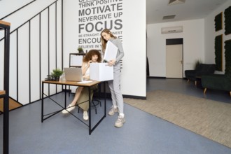 A woman looks into a box with the archives that her colleague brought to modern coworking