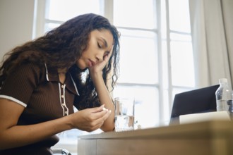 A woman experiences pain during menstruation and is forced to take painkillers while working
