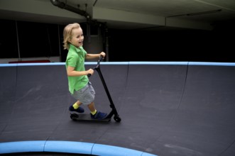 Boy, 6 years, blond, rides scooter, scooter, pump track, laughs, joy, Stuttgart, Baden-Württemberg,