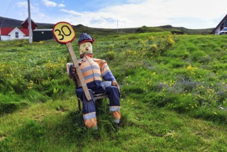 Funny traffic control, 30 km/h, speed limit, figure sits on summer meadow and holds self-made