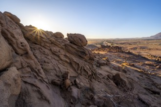 Eroded rock formations at sunrise with sun star, Erongo, Damaraland, Namibia