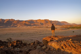 Young man in dry desert landscape, Brandberg in the morning light, at sunrise, Erongo, Damaraland,
