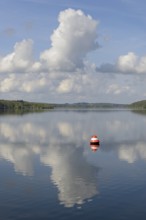 View over the Möhnesee, red and white buoy, blue cloudy sky, reflection on the water surface,