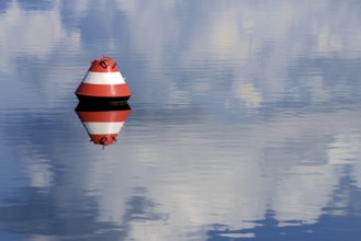 Red and white buoy and blue cloudy sky reflected on the surface of the water, Möhne Reservoir,