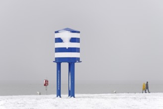 Winter day, onset of winter, snow on the North Sea coast, people walking on the beach promenade of