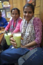 Indian blurred woman showing lassi or yoghurt drinks to the camera, Sandar Market Girdikot, old