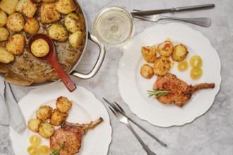 A delicious roasted pork rib roast is served alongside golden, crispy potatoes on elegant plates.