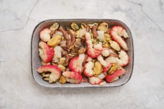 Overhead view of a bowl with shrimps, mussels, and squid. The dish showcases vibrant colors and