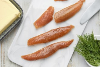Herring caviar are neatly arranged on a marble cutting board alongside a block of butter and fresh