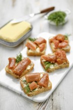 Pieces of toasted bread are topped with herring caviar and garnished with fresh herbs, arranged