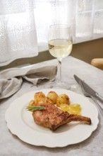 A perfectly roasted pork rib roast is plated alongside crispy golden potatoes and garnished with
