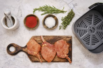 Marinated pork rib roast is seasoned with herbs and spices on a wooden cutting board while being