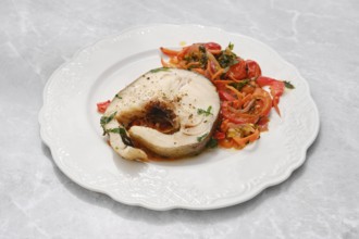 A succulent fish fillet, garnished with herbs, is presented alongside a colorful salad of sliced