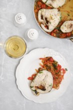 Tender cod fish fillet with colorful sautéed peppers, carrots and tomatoes on a plate on a dining