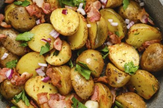Golden roasted potatoes are mixed with crispy bacon and garnished with fresh herbs and diced onions