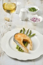A succulent piece of salmon on a plate with crispy asparagus spears. Accompanying the dish is a