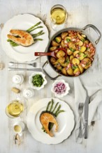 A beautifully arranged dining table features two plates of grilled salmon served with roasted