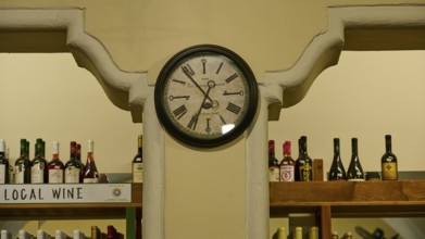 Agora, Municipal Market Hall, An antique clock on the wall of a wine shop with filled shelves, Kos