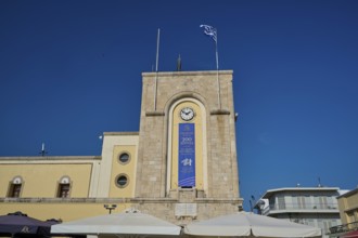 Cinema, Eleftherias Square, Historic clock tower with Greek flag against a clear sky, Kos Town,