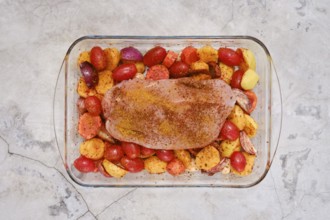 A perfectly seasoned turkey breast rests on a bed of vibrant potatoes, tomatoes and onion ready to