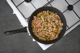 Seafood stir-fry with shrimp and mussels in a black pan, mixed with colourful herbs and spices on a