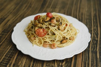 A delicious plate of spaghetti topped with shrimp and mussels, complemented by fresh cherry