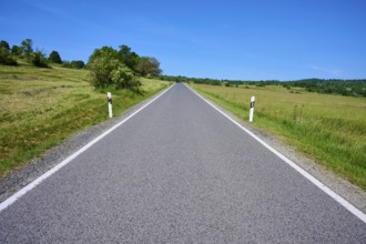Straight country road runs through open landscape with blue sky, summer, Franzosenweg, Lange Rhön,