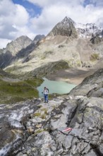 Mountaineer on a rocky hiking trail, view of the turquoise-blue mountain lake Großer Gradensee,