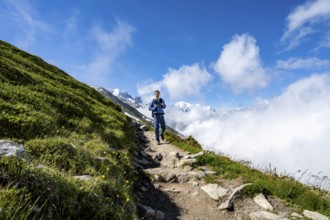 Mountaineer on a hiking trail, inversion weather situation with clouds in the valley, Chamonix,