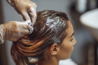 Beautiful Beautiful woman applying hair color to her hair in hairdressing salon, AI generated