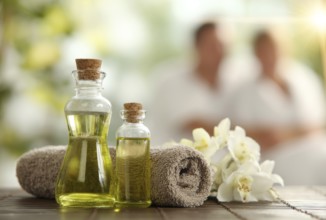 Beautiful spa composition with oil bottles and spa items and happy couple on background enjoying