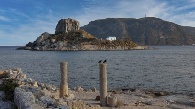 Stone columns in front of the sea with a view of an island under a slightly cloudy sky, Agios