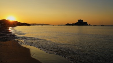 Tranquil sunset with a view of an island and golden sky, Agios Stefanos Beach, Agios Stefanos