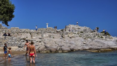 People and children exploring ancient ruins on the beach in sunny weather, Agios Stefanos Beach,
