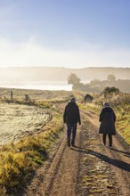 Pair walking on a gravel road in a rural landscape at autumn