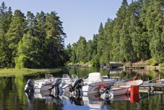 Motorboats at a jetty in a forest lake on a beautiful sunny summer day, Sweden