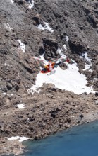 Red helicopter flying in the mountains, Stubai Alps, South Tyrol, Italy