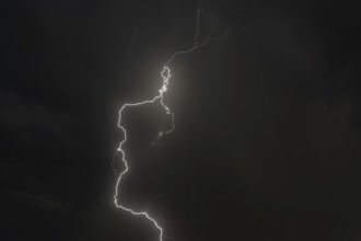 Dark clouds gather as lightning strikes light up the night. The intense storm brings thunder and