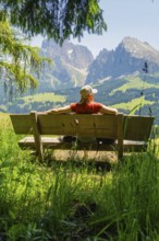 Person on a bench with a view of majestic mountains and vast landscape, Alpe di Siusi, Dolomites,